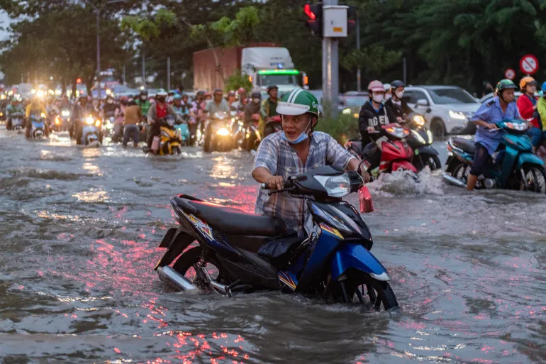 HO CHI MINH CITY, VIETNAM - NOVEMBER 6: People ride motorbikes on a street as water levels reach the annual peak on November 6, 2025 in Ho Chi Minh City, Vietnam. Ho Chi Minh City is one of the world’s fastest-sinking coastal cities and has seen worsening flooding due to climate change, rising sea levels, and rapid urbanization. According to the World Bank, a 40 cm rise in sea level could cause yearly losses of 1–5% of the city’s GDP. (Photo by Thanh Hue/Getty Images)