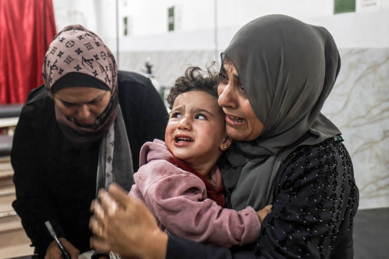 A woman holds a baby crying.