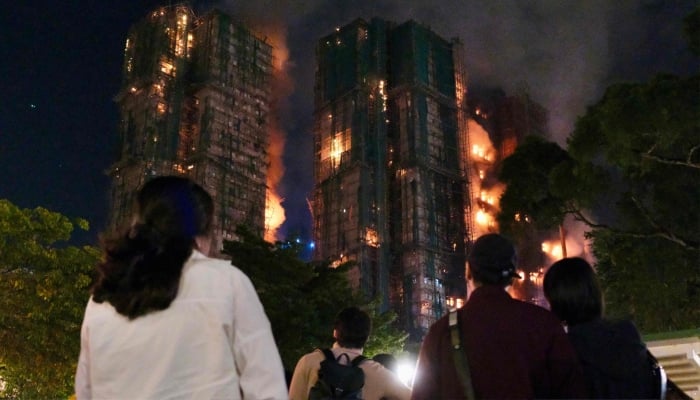 People look on as thick smoke and flames rise during a major fire at the Wang Fuk Court residential estate in Hong Kong´s Tai Po district, November 26, 2025. — AFP