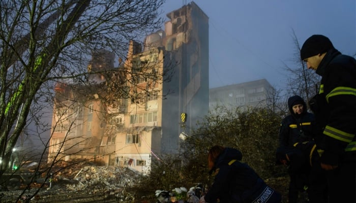 A psychologist sits beside toys and flowers placed near a heavily damaged residential building following Russian air strike in the city of Ternopil, November 20, 2025. — AFP