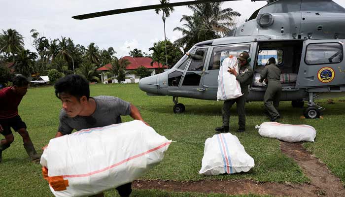 A man moves a relief supply package delivered by a Navy helicopter in an area affected by deadly flash floods in Palembayan, Agam regency, West Sumatra province, Indonesia on November 30, 2025. — Reuters