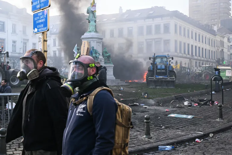 Farmers wear gas masks at the Place du Luxembourg near the European Parliament, during a farmers' protest to denounce the reforms of the Common Agricultural Policy (CAP) and trade agreements such as the Mercosur, in Brussels, on December 18, 2025, organised by Copa-Cogeca, the main association representing farmers and agricultural cooperatives in the EU. EU Farmers, particularly in France, worry the Mercosur deal -- which will be discussed at the EU leaders meeting -- will see them undercut by a flow of cheaper goods from agricultural giant Brazil and its neighbours. They also oppose plans put forward by the European Commission to overhaul the 27-nation bloc's huge farming subsidies, fearing less money will flow their way. (Photo by NICOLAS TUCAT / AFP)