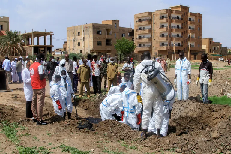 Members of the Sudanese Red Crescent and forensic experts exhume the remains of people from makeshift graves for reburial in the local cemetery in Khartoum's southern suburb of al-Azhari on August 2, 2025 after the dead were buried in a rush when the area was under control of the Rapid Support Forces (RSF) paramilitaries. In Sudan's war-scarred capital Khartoum, Red Crescent volunteers have begun the grisly task of exhuming the dead from makeshift plots where they were buried during the fighting so their families can give them a proper funeral. (Photo by Ebrahim Hamid / AFP)