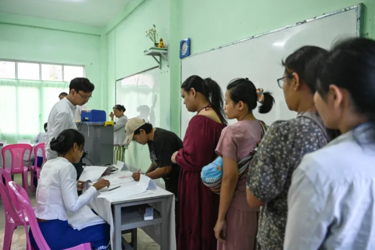 People line up to vote inside a polling station during the first phase of Myanmar's general election in Yangon on December 28, 2025.Polling opened in Myanmar's heavily restricted junta-run elections, beginning a month-long vote democracy watchdogs describe as a rebranding of military rule.