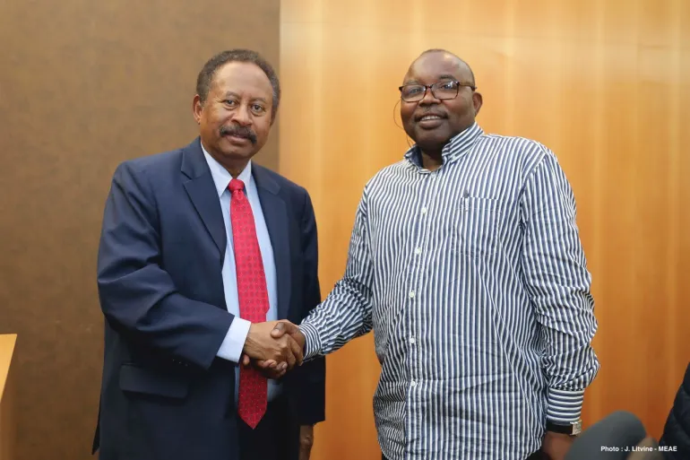 Abdallah Hamdok on the left in a suit and Abdel Wahid Nur on the right in a striped shirt