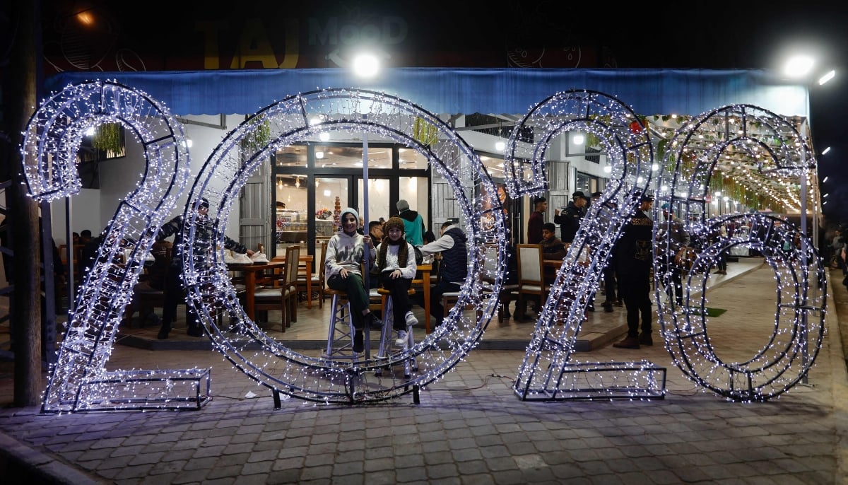 Palestinians sit in front of New Years decorations in Gaza City on December 31, 2025. — AFP