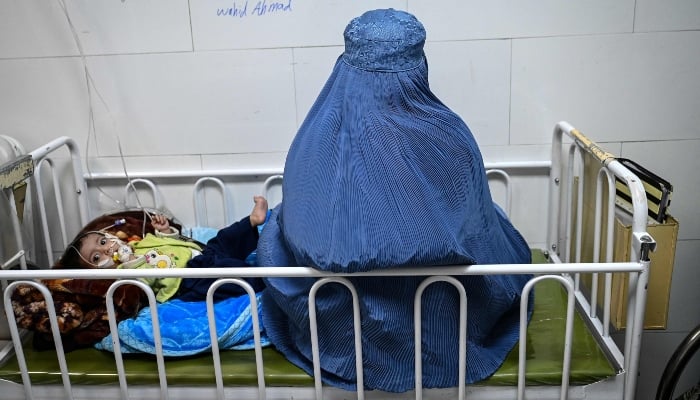 This photograph, taken on January 8, 2026, shows an Afghan woman sitting next to her malnourished child inside the Medecins Sans Frontieres (MSF) therapeutic nutrition centre at a hospital in Herat, Afghanistan. — AFP