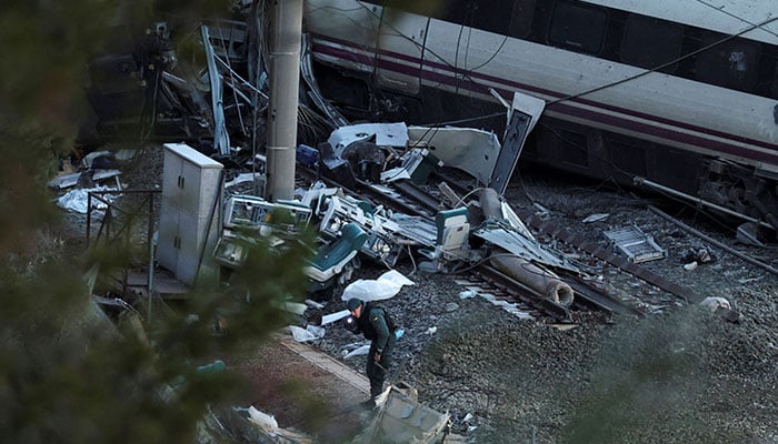 A member of the Spanish Civil Guard searches underneath the wreckage of a train involved in the accident, at the site of a deadly derailment of two high-speed trains near Adamuz, in Cordoba, Spain on January 20, 2026. — AFP