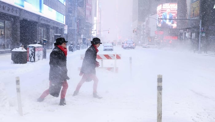 People walk across Sixth Avenue as snow falls in New York City, US, on January 25, 2026. — AFP