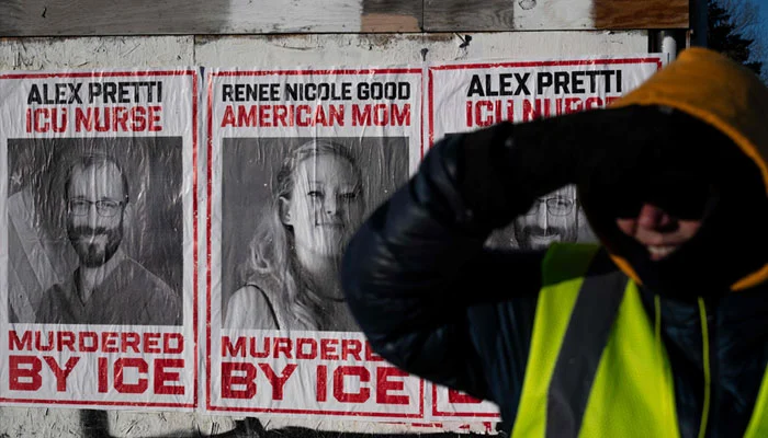 Backdropped by posters with images of Renne Good and Alex Pretti, the two US citizens recently shot and killed by federal immigration officers, a resident of Minneapolis mans a corner to keep an eye out for ICE agents near a school where some students were recently arrested in Minneapolis, Minnesota, on January 29, 2026. — AFP