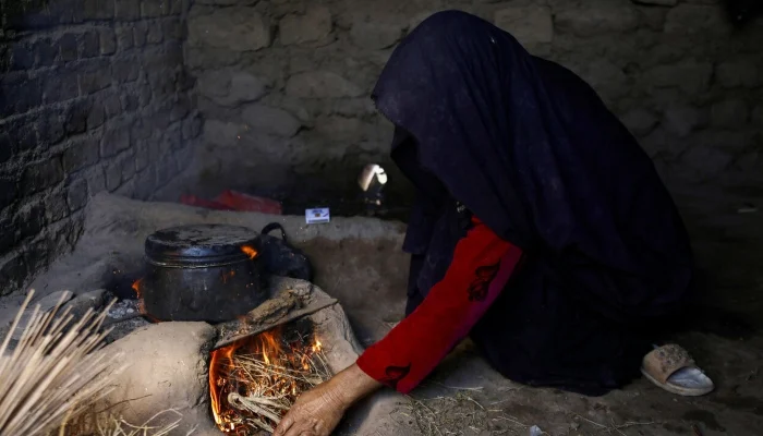 An Afghan woman lights a fire to cook food at a makeshift kitchen in Markhor-e-Sufla village, Herat, Afghanistan, October 26, 2024. — Reuters