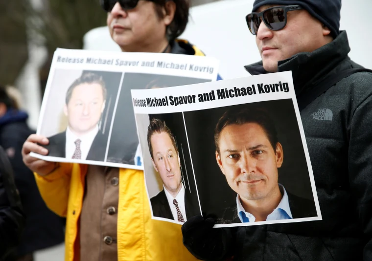 Image: People hold signs calling for China to release Canadian detainees Spavor and Kovrig during an extradition hearing for Huawei Technologies Chief Financial Officer Meng Wanzhou at the B.C. Supreme Court in Vancouver
