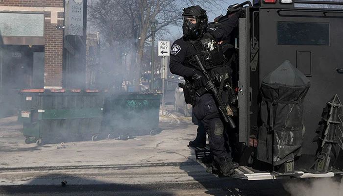 A Minneapolis Police Department officer rides on the back of a vehicle, during clashes with community members at the scene where federal agents fatally shot a man while trying to detain him, in Minneapolis, Minnesota, US, January 24, 2026. — Reuters