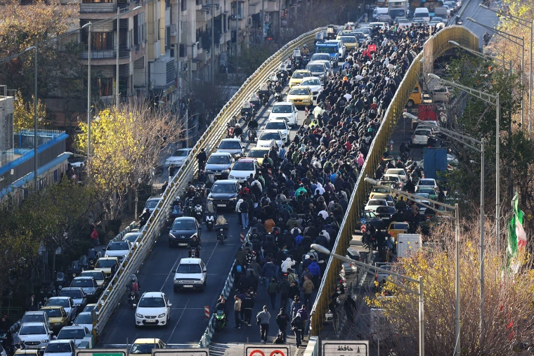 Shopkeepers and traders walk over a bridge during a protest against the economic conditions and Iran's embattled currency in Tehran on Dec. 29, 2025. 