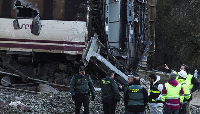Members of the Spanish Civil Guard and ADIF stand near the wreckage of a train involved in the accident, at the site of a deadly derailment of two high-speed trains near Adamuz, in Cordoba, Spain on January 20, 2026. — Reuters