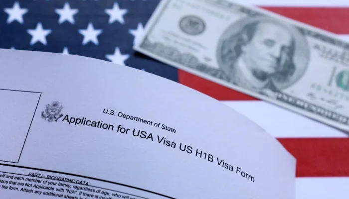 US flag, mock passport, 100 dollar banknote and H-1B visa application form are seen in this illustration taken September 26, 2025. — Reuters