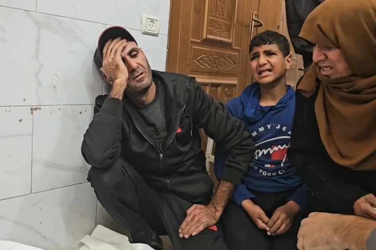 Rami Essam Abu Jamea and his family members cry while kneeling on the floor
