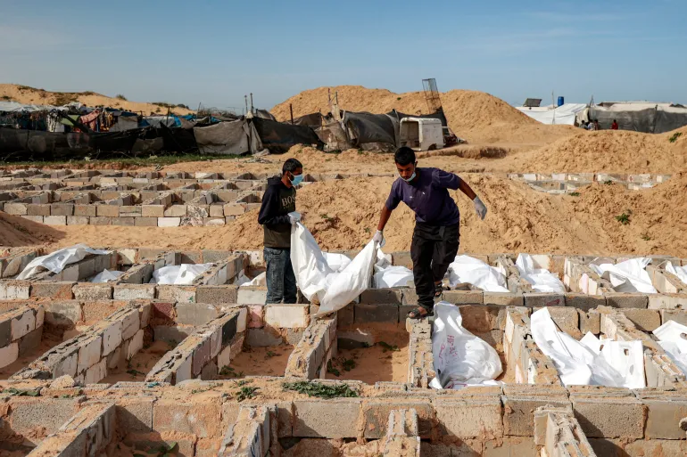 EDITORS NOTE: Graphic content / Men carry a body bag as they bury one of 53 unidentified bodies at a cemetery in Deir el-Balah in the central Gaza Strip on February 13, 2026.