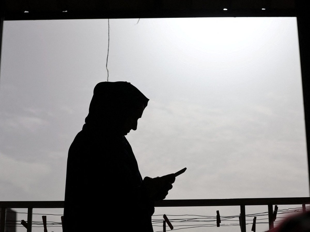 Faten Hamed Abu Watfa, a 43-year-old Palestinian mother who travelled to Egypt to accompany her mother-in-law for medical treatment and now longs to return to Gaza, where her three children remain, once the Rafah border crossing reopens, checks her phone while stand on a balcony, in Cairo, Egypt, January 31, 2026. PHOTO: REUTERS/Mohamed Abd El Ghany