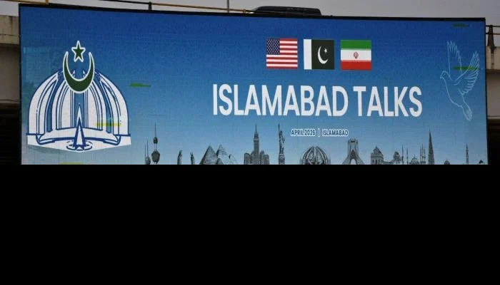 A man rides his motorbike past a billboard installed alongside a road as as delegations from the United States and Iran are expected to hold peace talks in Islamabad, April 11, 2026. — Reuters