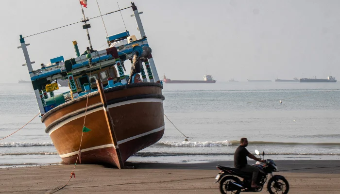 In this picture obtained from Irans ISNA news agency on April 24, 2026, an Iranian man rides his motorcycle past a boat at Suru Beach in Bandar Abbas along the Strait of Hormuz. — AFP