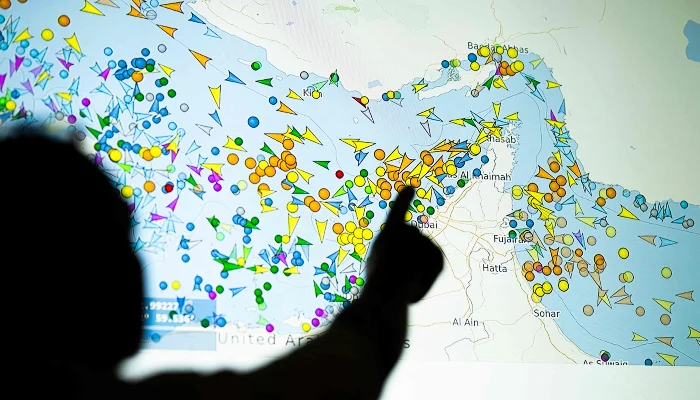 A photo illustration taken in Nicosia on May 4, 2026, shows a person in front of a large screen displaying vessel movements in the Strait of Hormuz on a ship-tracking website. — AFP