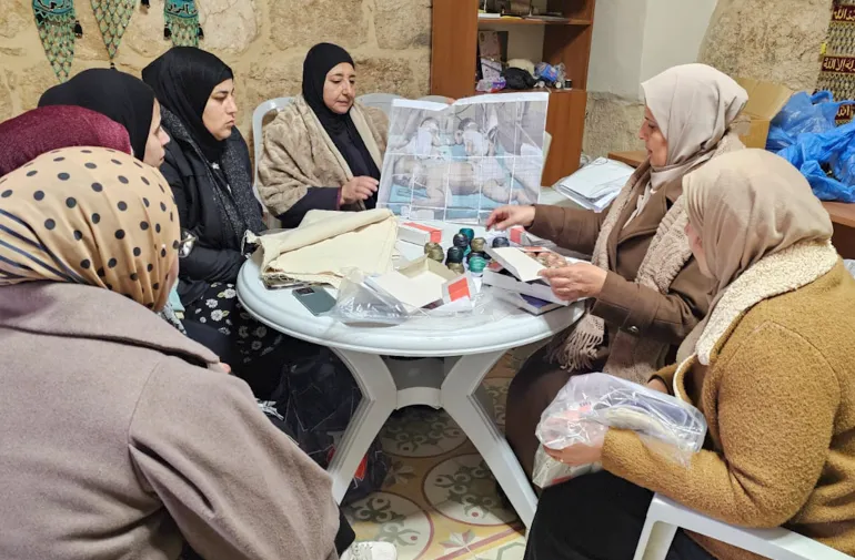 A group of Palestinian embroiderers coneve to perpare panels for stitch. Al-Samou', occupied West Bank. (Courtesy of Palestine Museum US)-1778317102