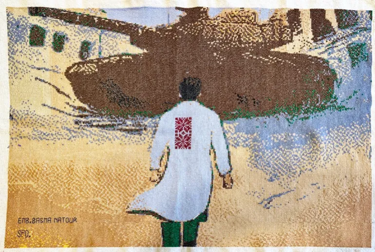 An embroidery of the scene in which Dr Hussam Abu Safiya heads to an Israeli tank