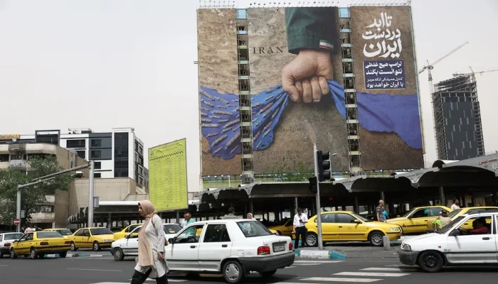 People walk past a billboard with a graphic design about the Strait of Hormuz on a building, in Tehran, Iran, May 4, 2026. — Reuters