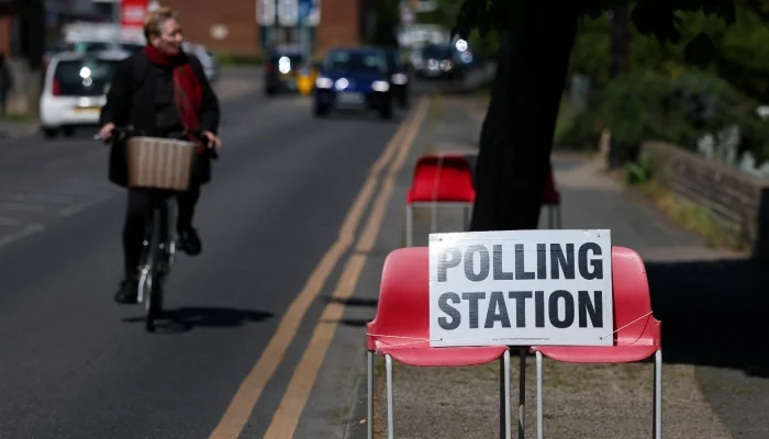 A person cycles near a sign placed on chairs outside a polling station during local elections in Jaywick, near Clacton-on-Sea, Britain, May 7, 2026. — Reuters