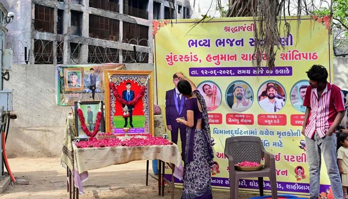 Family members of Air India plane crash victim Akash Patni pay tribute at remembrance portraits set up for him at the crash site on the first anniversary of the disaster in Ahmedabad on June 12, 2026. — AFP