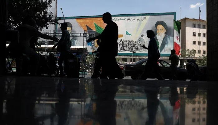 People walk near a mural depicting the late leader of the Islamic Revolution, Ayatollah Ruhollah Khomeini, and Irans late Supreme Leader Ayatollah Ali Khamenei, on a street in Tehran, Iran, June 14, 2026.