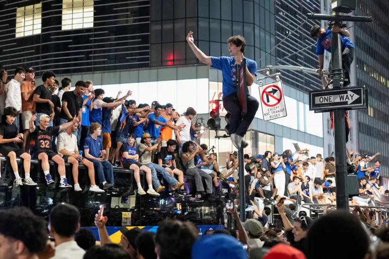 Fans celebrate the New York Knicks' win against the San Antonio Spurs in Game 5 of the NBA Finals, on a street near Madison Square Garden, in New York City, U.S., June 14, 2026. REUTERS/Christian Monterrosa