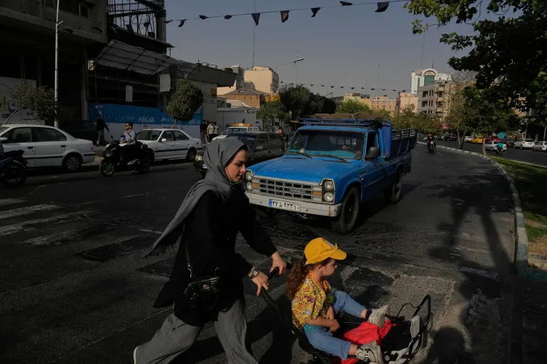 A woman and girl cross a street in central Tehran on July 22, 2026