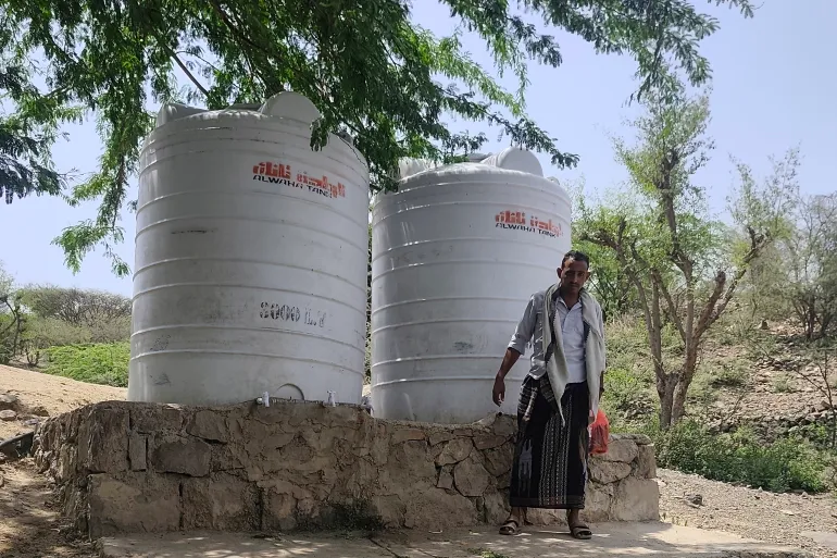 Abdulaziz Shamsan stands beside water tanks near the camp for displaced families where he lives [Courtesy of Abdulaziz Shamsan]