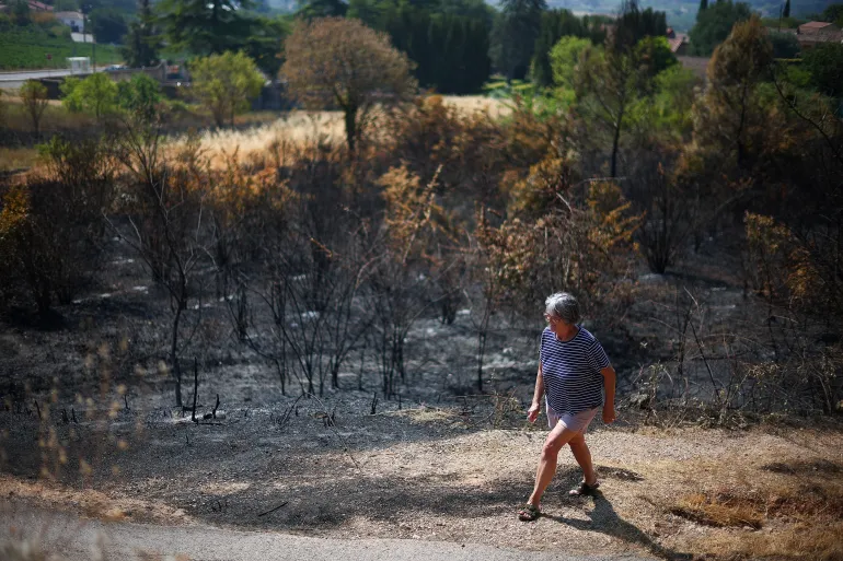 A person walks by an area burnt by fire, in Montfort-sur-Argens, in the Var department, amid worsening drought conditions following a heatwave and water shortages across much of France, August 2, 2026. REUTERS/Florion Goga