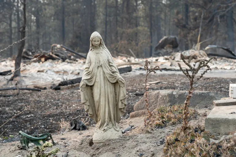 A Virgin Mary statue remains untouched in front of a burned out residential home in the Balboa neighborhood of Spokane, Washington, on August 2, 2026.