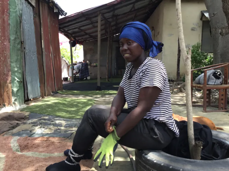Fatou prepares for a day of crab harvesting, pulling on her gloves before venturing into the mangrove forest