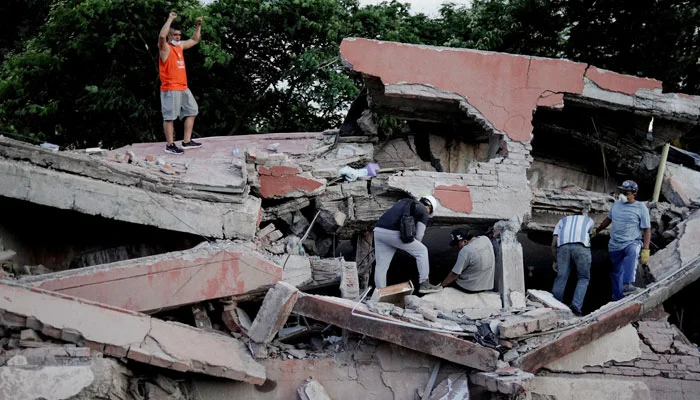 A rescue worker raises his fists to call for silence to locate victims under the rubble at the site of a collapsed building following an earthquake, in Cali, Colombia, August 10, 2026.— Reuters