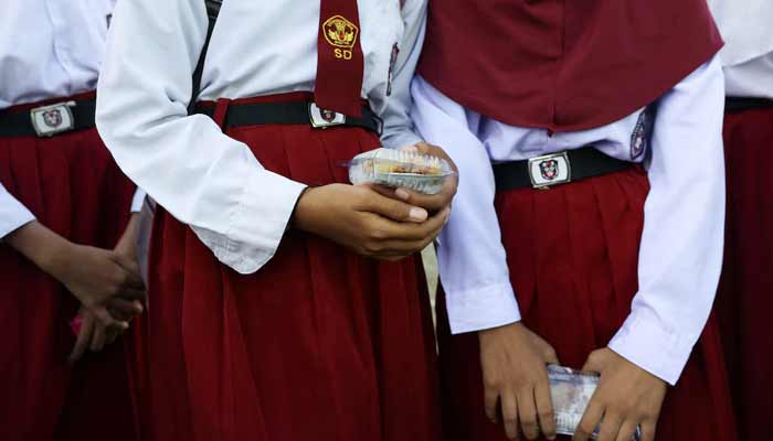 Students hold chicken rice in a plastic container at an elementary school in the fishing village of Torosiaje, Gorontalo province, Indonesia, July 27, 2026.— Reuters