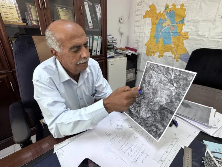 Mayor Suleiman Khourieh looking at a map of the closed military zone around Taybeh [Al Jazeera]