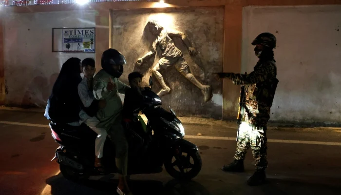 An Indian security personnel signals a scooterist riding with a family to change his route after the road leading to the venue for Indias Independence Day celebrations was closed for traffic, in Srinagar, Indian Illegally Occupied Jammu and Kashmir, August 14, 2026.