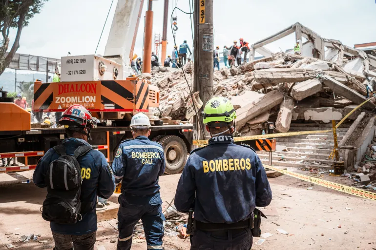 Three firemen approach the wreckage of the Vanessa apartment building in Cali, which collapsed on August 10 and now shows no signs of survivors. [Euan Wallace / Al Jazeera]