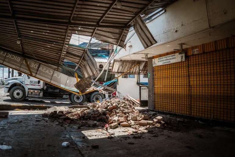 The damage to the building that houses Néstor Martínez’s bicycle shop, where part of the roof has collapsed. [Euan Wallace / Al Jazeera]