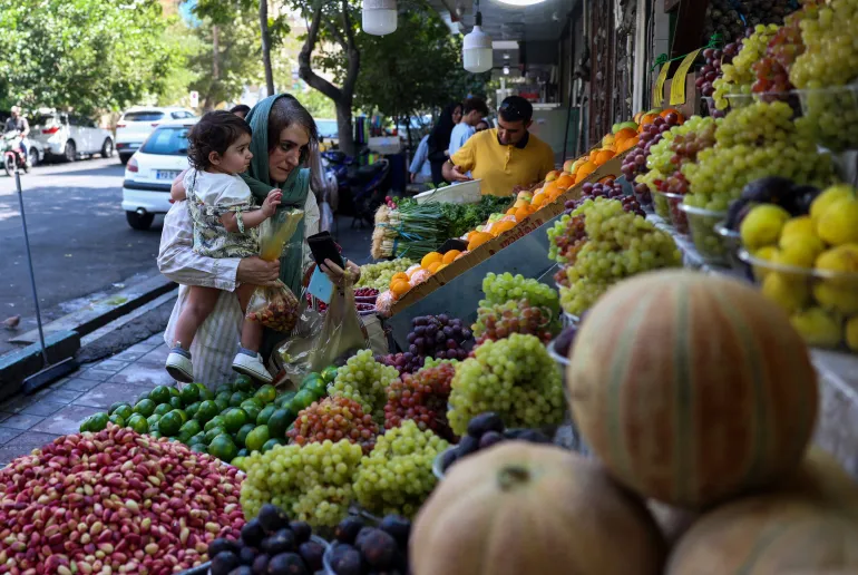 A woman buys fruits from a store in Tehran on August 24, 2026. Iran responded with defiance on August 24 to a US threat of the "single greatest financial offensive ever", saying it was an admission of military defeat and warning countries against aiding Washington. (Photo by AFP) /