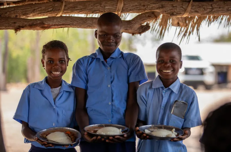 Schoolchildren pose with nutrition meals provided by the United Nations World Food Programme as communities recover from flooding in Mozambique. [WFP Mozambique]