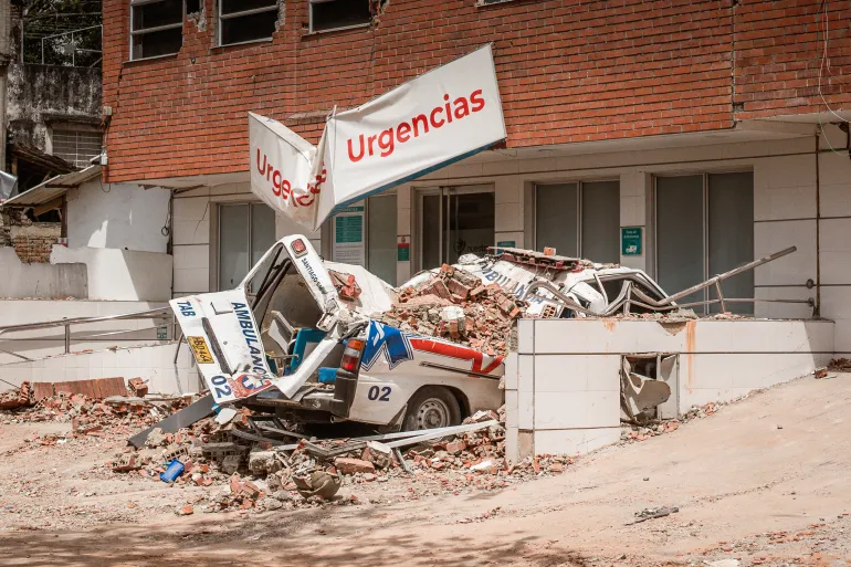An ambulance crushed by falling debris from the “Clinica Nuestra” private hospital in Cali, which partially collapsed during the August 10 earthquake. [Euan Wallace / Al Jazeera]
