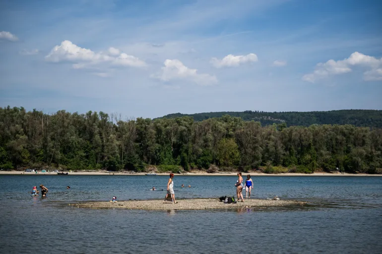 People spend time on a newly exposed island due to the low water level of the Danube River in Kisoroszi, Hungary, August 1, 2026. REUTERS/Marton Monus