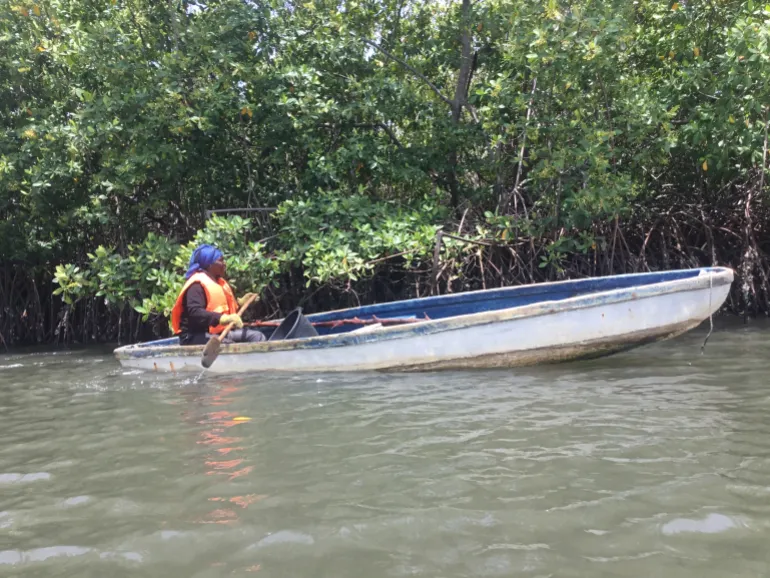 Fatou pushes her canoe into the water, beginning another day of searching for crabs in the mangrove wetlands that sustain her livelihood