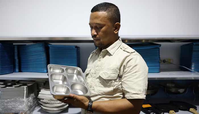 Sigit Buludawa, 34, owner of a kitchen serving the National Nutrition Agencys (NNA) free meal programme in a remote area, holds a tray while posing for a photograph in the fishing village of Torosiaje, Gorontalo province, Indonesia, July 27, 2026.— Reuters